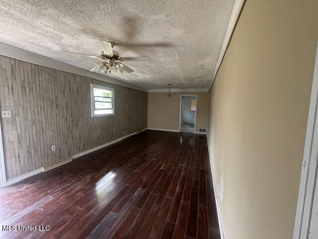 unfurnished living room featuring a textured ceiling, ceiling fan, wood finished floors, baseboards, and ornamental molding