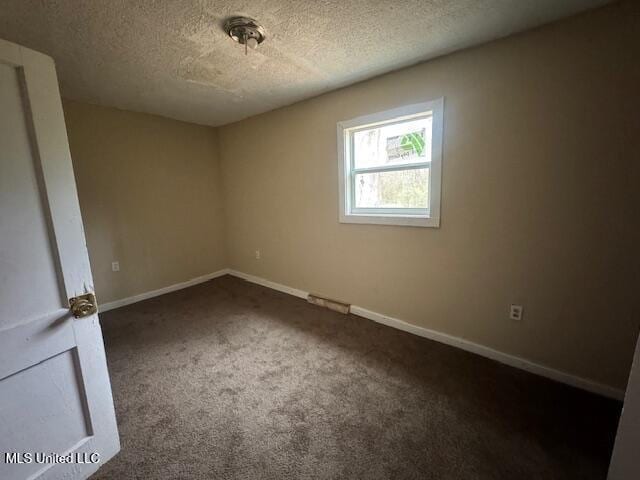 carpeted empty room featuring a textured ceiling and baseboards