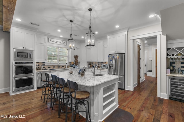 kitchen with a center island with sink, decorative backsplash, appliances with stainless steel finishes, and white cabinets