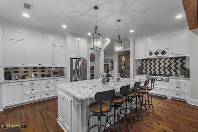 kitchen with appliances with stainless steel finishes, dark wood-type flooring, a center island, and white cabinets