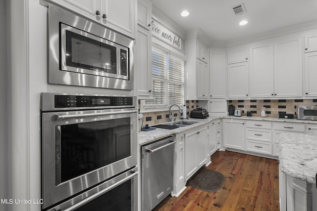 kitchen featuring appliances with stainless steel finishes, white cabinetry, sink, and backsplash