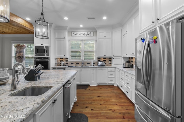 kitchen with sink, hanging light fixtures, stainless steel appliances, white cabinets, and dark wood-type flooring