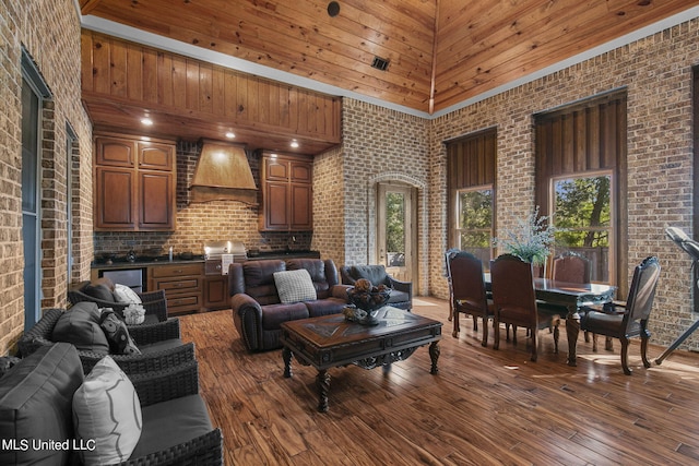 living room featuring a towering ceiling, hardwood / wood-style floors, and brick wall