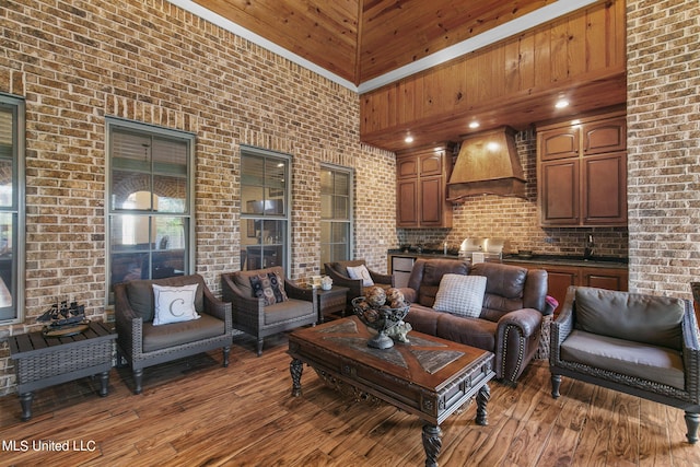 living room with brick wall, a high ceiling, wood-type flooring, and sink