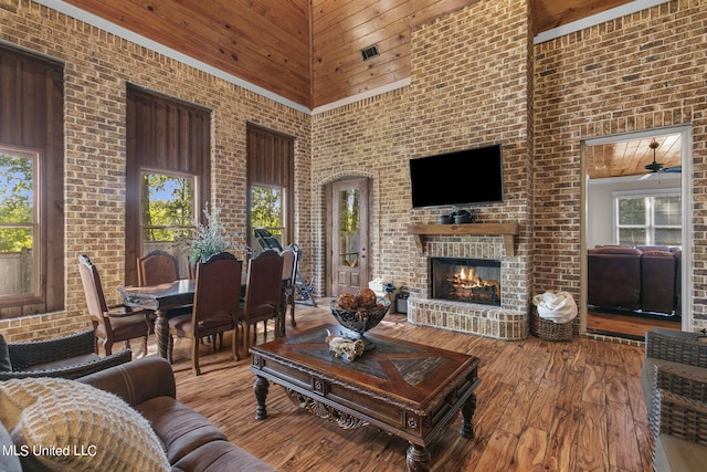 living room with brick wall, a brick fireplace, wood-type flooring, and high vaulted ceiling