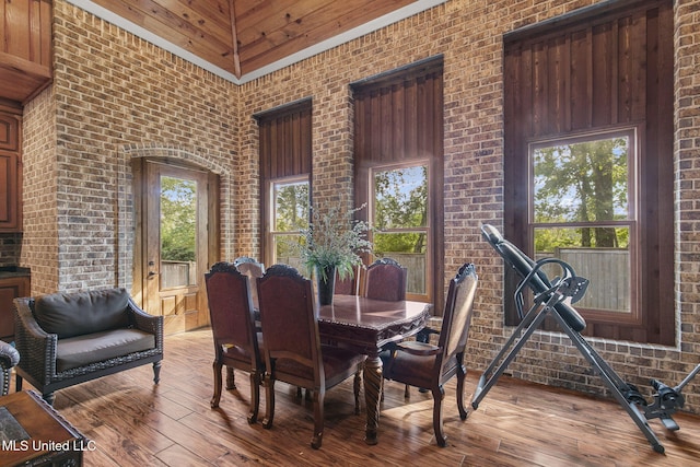 dining room featuring brick wall and a healthy amount of sunlight