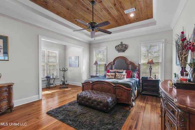 bedroom with wood ceiling, ceiling fan, a raised ceiling, ornamental molding, and dark wood-type flooring