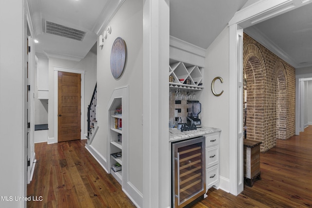 bar featuring ornamental molding, brick wall, and beverage cooler