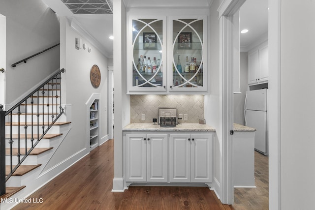 bar with light stone countertops, dark hardwood / wood-style flooring, white refrigerator, and white cabinets