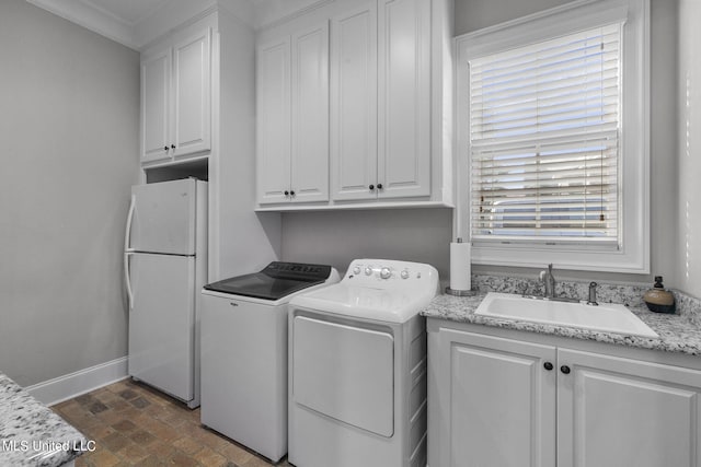 clothes washing area with crown molding, washer and dryer, sink, and a wealth of natural light