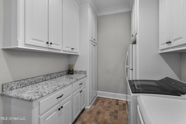 213 Ironwood Plantation Blvd, Madison, MS 39110 - laundry area featuring crown molding, washing machine and dryer, baseboards, brick floor, and cabinet space