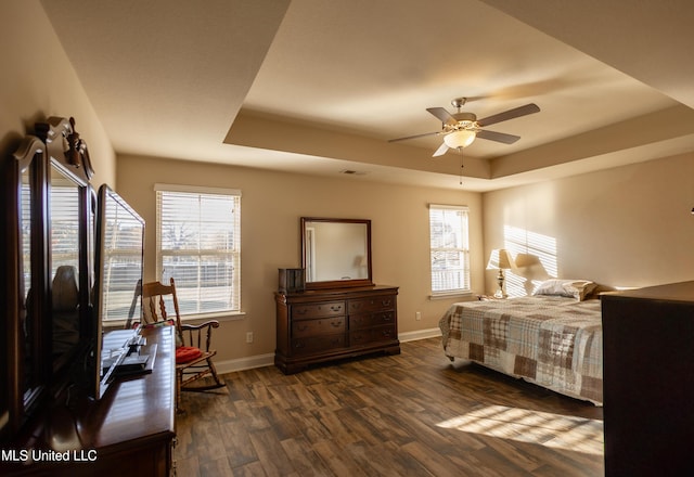 bedroom with a raised ceiling, ceiling fan, and dark hardwood / wood-style flooring