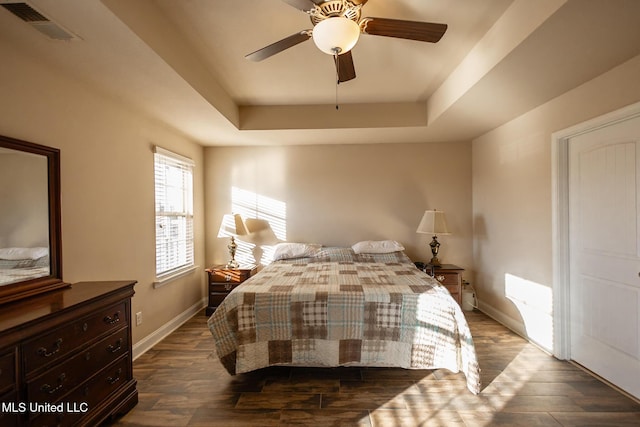 bedroom featuring dark hardwood / wood-style floors, a raised ceiling, and ceiling fan