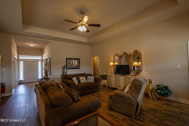 living room with ceiling fan, dark hardwood / wood-style floors, and a tray ceiling