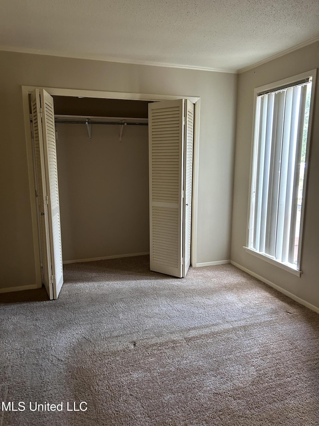 150 Lakeside Villa Unit J, Diamondhead, MS 39525 - unfurnished bedroom with a closet, carpet, a textured ceiling, baseboards, and crown molding