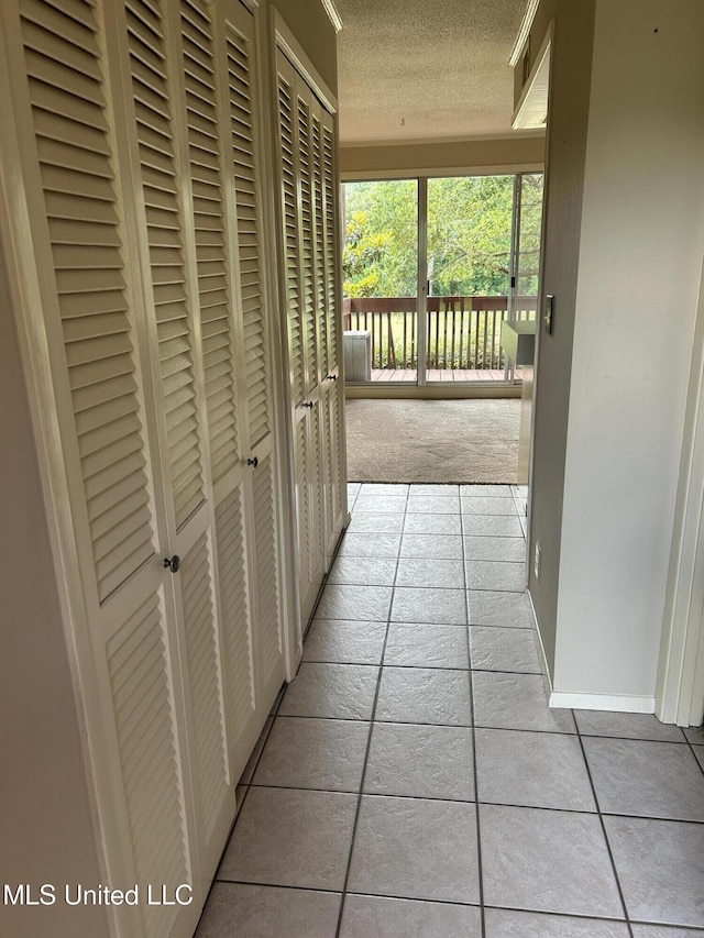 150 Lakeside Villa Unit J, Diamondhead, MS 39525 - hall with tile patterned floors, a textured ceiling, carpet flooring, and baseboards