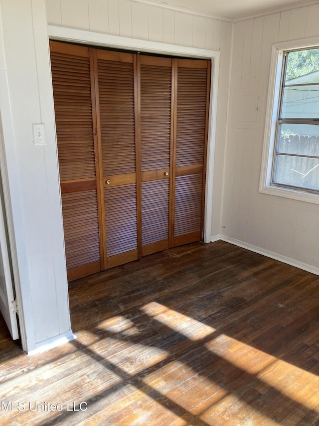 unfurnished bedroom featuring hardwood / wood-style floors, a closet, and baseboards