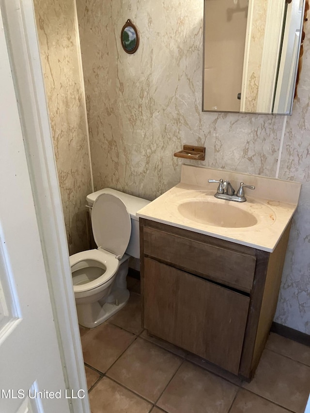 bathroom featuring tile patterned flooring, vanity, toilet, and wallpapered walls