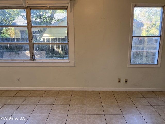unfurnished room featuring baseboards, plenty of natural light, and light tile patterned floors
