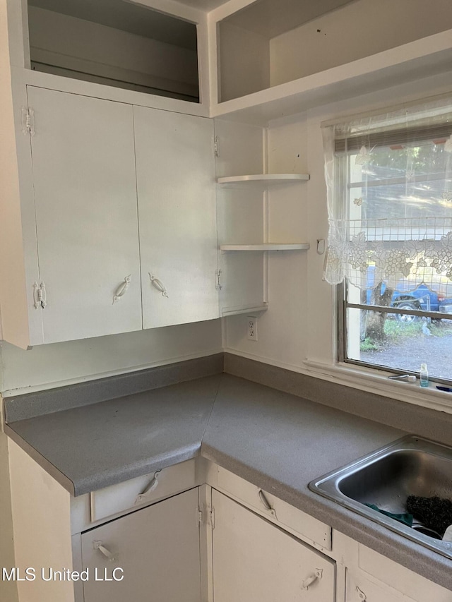 kitchen with open shelves, white cabinetry, and dark countertops