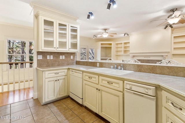 kitchen with cream cabinets, white dishwasher, sink, light tile patterned flooring, and tasteful backsplash