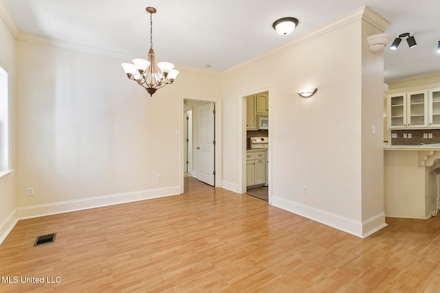 unfurnished room with an inviting chandelier, crown molding, and light wood-type flooring