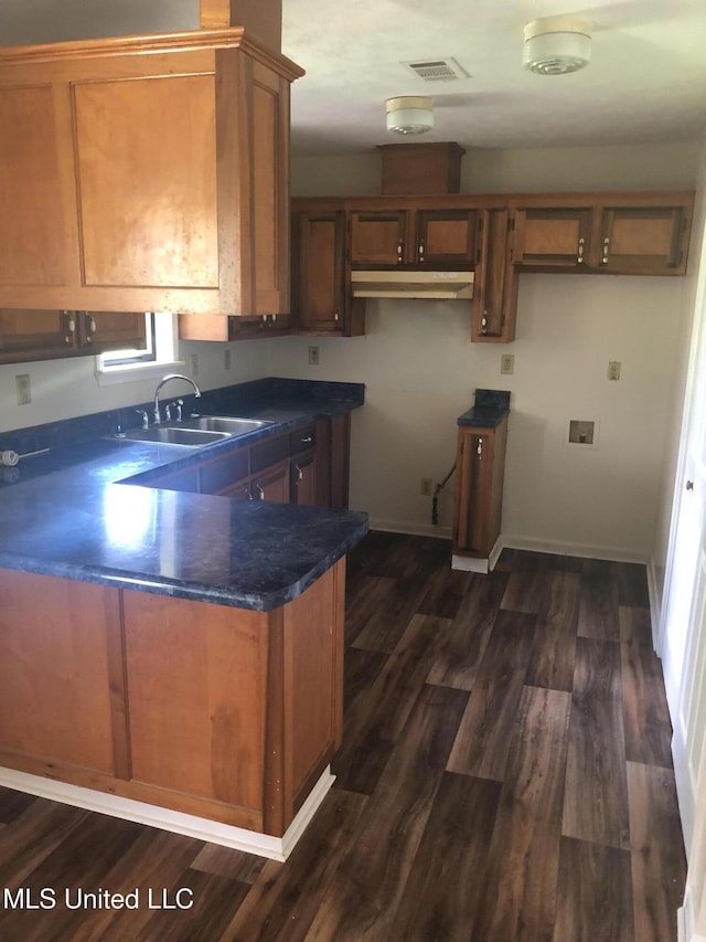 69 Wiley Ave, Durant, MS 39063 - kitchen with brown cabinetry, dark countertops, dark wood-style flooring, and a peninsula
