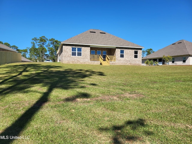 back of property featuring brick siding, a lawn, and a shingled roof