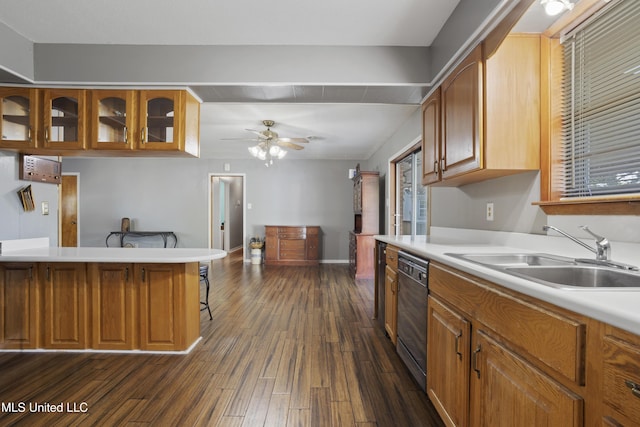 kitchen featuring dishwashing machine, a kitchen bar, dark wood-type flooring, light countertops, and a sink