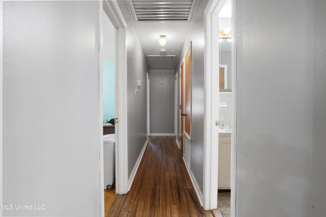 hall featuring visible vents, attic access, wood-type flooring, and baseboards