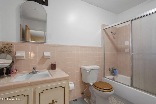 bathroom with vanity, toilet, enclosed tub / shower combo, a wainscoted wall, and tile walls