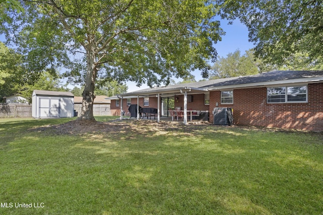 rear view of property featuring fence, a shed, brick siding, a patio area, and a lawn