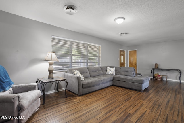living room with a textured ceiling, baseboards, and wood finished floors