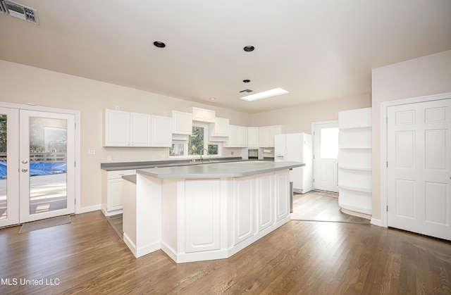 kitchen featuring a wealth of natural light, white cabinetry, a kitchen island, and white refrigerator with ice dispenser