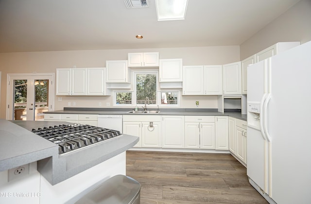 kitchen with white cabinets, wood-type flooring, white appliances, and sink