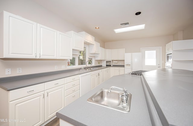 kitchen with white cabinetry, sink, and white appliances