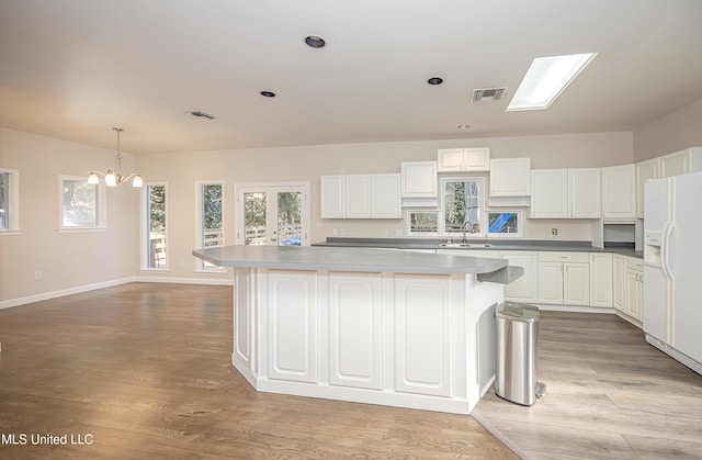 kitchen with white cabinetry, white fridge with ice dispenser, a chandelier, and sink