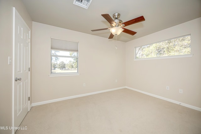 carpeted spare room featuring ceiling fan and a healthy amount of sunlight