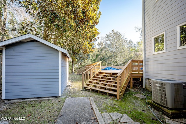 view of yard with a wooden deck, central AC unit, and a storage shed