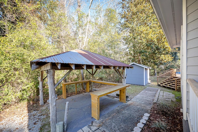 view of patio featuring a gazebo, a storage unit, and a wooden deck