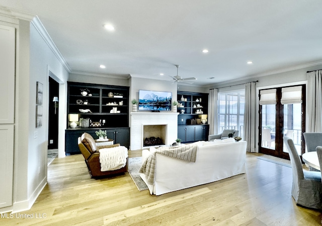 living area featuring light wood finished floors, a fireplace, crown molding, and recessed lighting