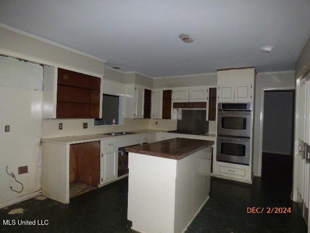 kitchen featuring sink, a kitchen island, double oven, and white cabinets