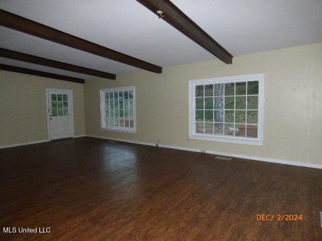 spare room featuring vaulted ceiling with beams and dark wood-type flooring