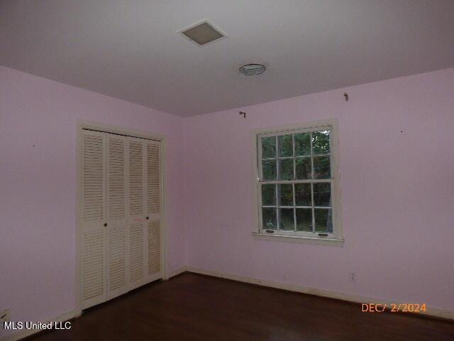 unfurnished bedroom with a closet and dark wood-type flooring