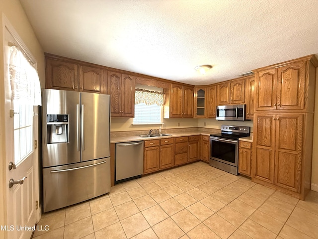1606 Woodhaven St, Pascagoula, MS 39581 - kitchen featuring stainless steel appliances, brown cabinetry, light tile patterned floors, light countertops, and a sink