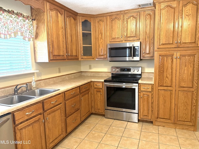 1606 Woodhaven St, Pascagoula, MS 39581 - kitchen with appliances with stainless steel finishes, brown cabinetry, a sink, and light tile patterned flooring