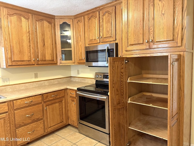1606 Woodhaven St, Pascagoula, MS 39581 - kitchen featuring stainless steel appliances, brown cabinets, glass insert cabinets, and a textured ceiling