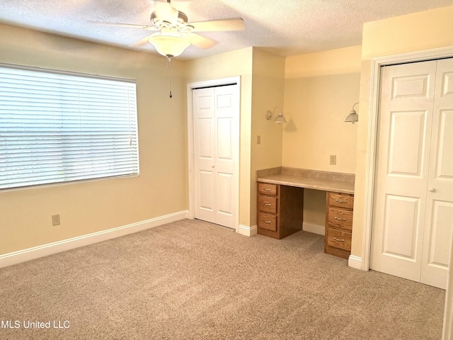 1606 Woodhaven St, Pascagoula, MS 39581 - unfurnished office with light colored carpet, ceiling fan, a textured ceiling, built in desk, and baseboards