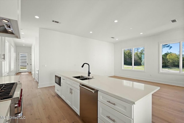 kitchen featuring stainless steel appliances, a kitchen island with sink, sink, light hardwood / wood-style flooring, and white cabinets