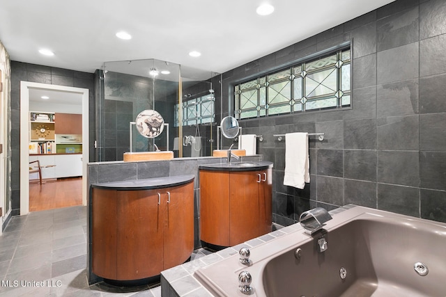 bathroom featuring vanity, plus walk in shower, tile walls, and tile patterned flooring